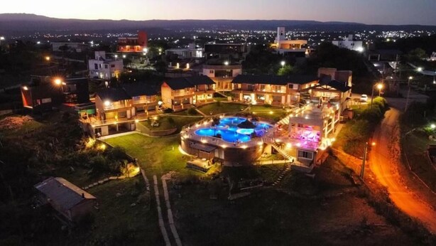 A resort with multiple buildings, a central pool area, and a surrounding landscape. - ERNESTINA VILLAGE (Villa Carlos Paz)