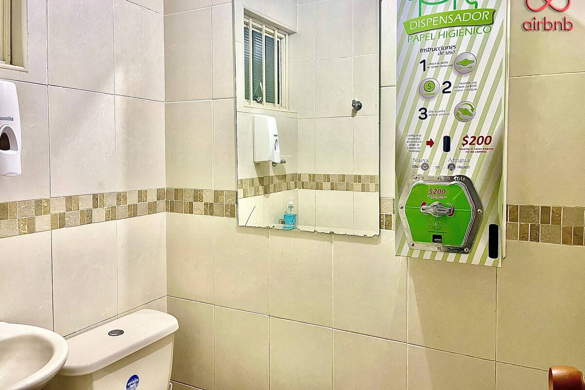 A bathroom with a toilet, a hand dryer, and a paper towel dispenser.