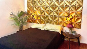 A bedroom with a bed, a nightstand, a potted plant, and a decorative wall panel. - A 5 minutos del aeropuerto (Bogotá)