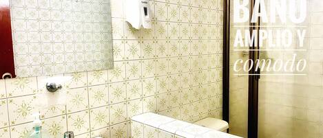 Un baño con baldosas estampadas, un lavamanos, un secador de manos y un inodoro.