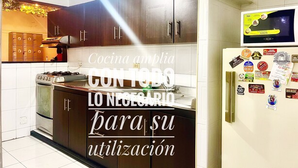 A kitchen with dark wooden cabinets, a stove, and a refrigerator covered in magnets. - A 5 minutos del aeropuerto (Bogotá)