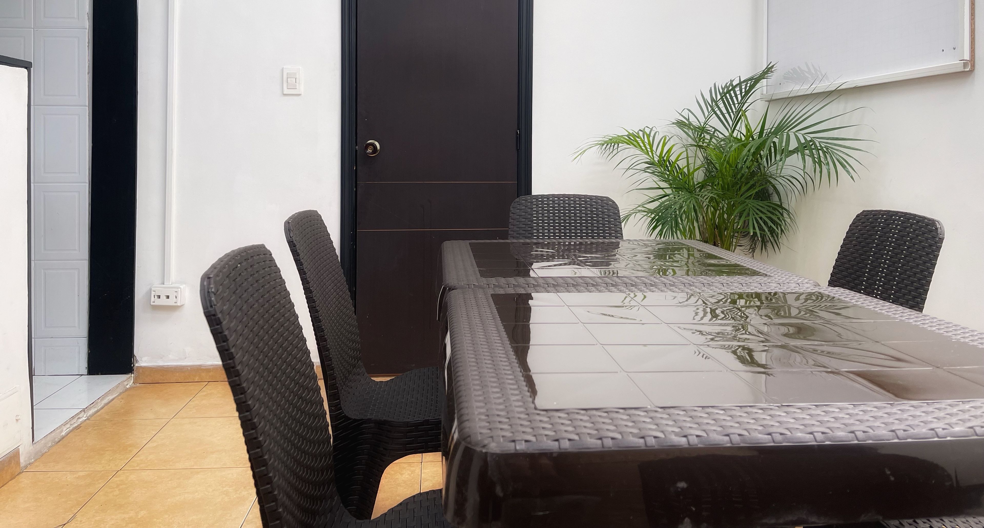 Een vergaderruimte met een tafel met glazen blad, zwarte stoelen, een deur met het nummer 3 en een potplant.