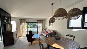 A modern living room with a dining area, large windows, and a balcony. - Villas Ambiance 21 Elégance Méditerranéenne à Portiragnes, Entre Terre et mer (Portiragnes)