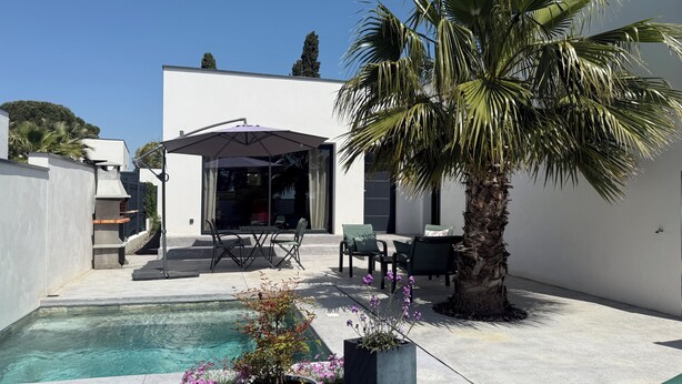 A modern outdoor pool area with a patio, seating, and a palm tree. - Villas Ambiance 21 Elégance Méditerranéenne à Portiragnes, Entre Terre et mer (Portiragnes)
