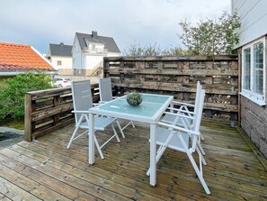 A wooden deck with a glass table and white chairs, surrounded by a wooden fence. - 4 Person Holiday Home in Kungshamn (Kungshamn)