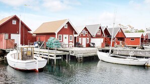 A row of red wooden houses with docks, boats, and a clear sky. - 4 Person Holiday Home in Kungshamn (Kungshamn)
