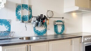 A kitchen with a sink, cabinets, and a stove. There are kitchen utensils hanging on a rack. - 4 Person Holiday Home in Kungshamn (Kungshamn)