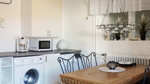 A compact kitchen with a washing machine, microwave, and coffee maker. - 4 Person Holiday Home in Kungshamn (Kungshamn)