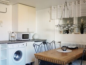 A compact kitchen with a washing machine, microwave, and coffee maker.