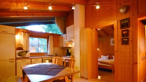 Une charmante cabane en bois comprenant un coin repas, une cuisine et une chambre.