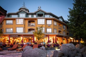 En byggnad med flera våningar, där restaurangen "All Seasons Grill" ligger på bottenvåningen. Restaurangen har uteservering och ett stenbelagt område med stora stenblock.