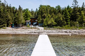 A wooden dock leading to a house surrounded by dense forest.