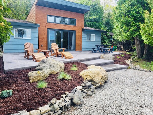 A modern house with a patio, outdoor seating, and a stone pathway.