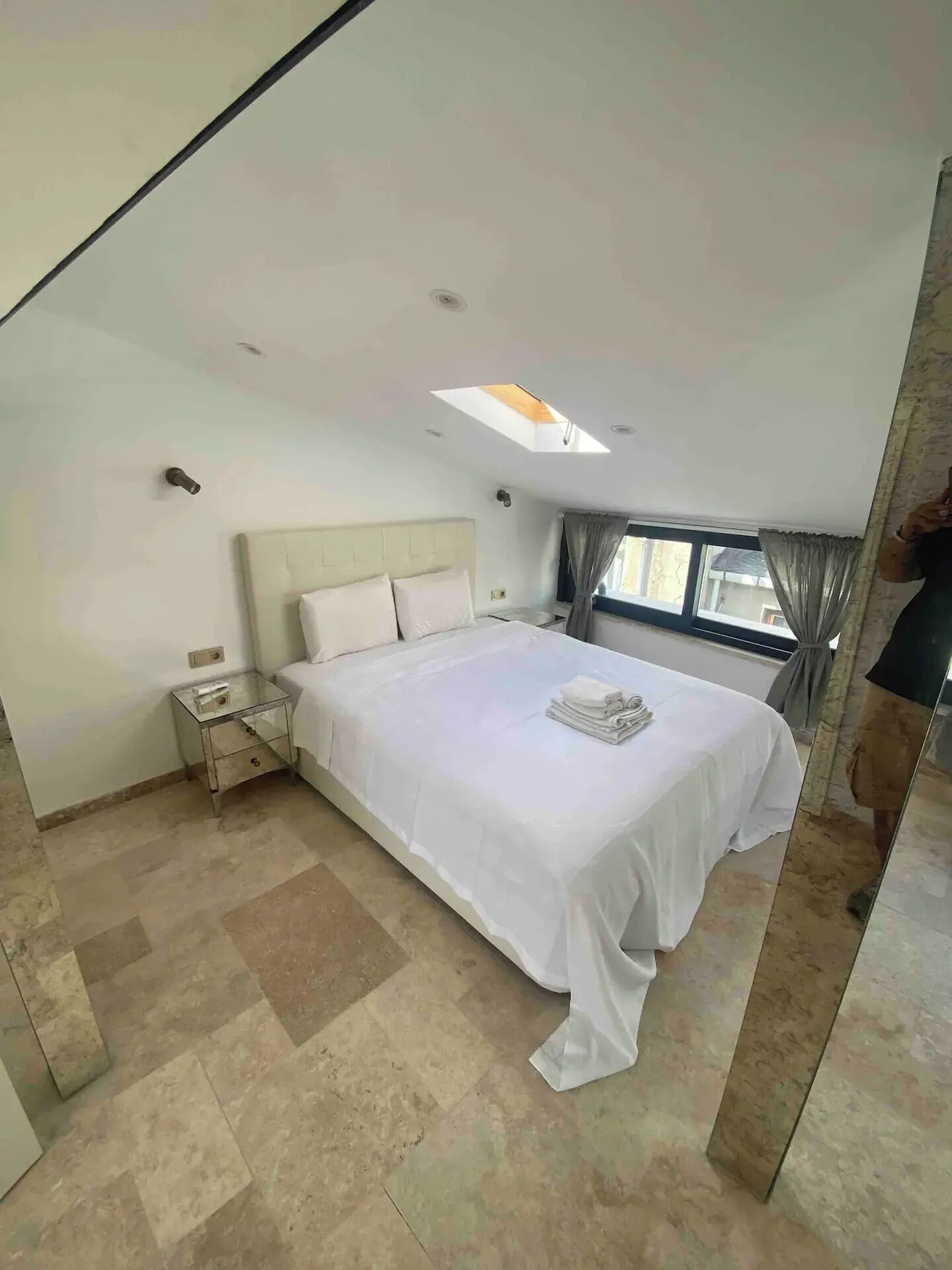 Ein modernes Schlafzimmer mit einem großen Bett, einem Nachttisch und einem Dachfenster.