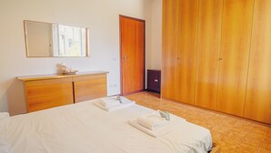 Een slaapkamer met een bed, een kaptafel, een spiegel en een kledingkast.