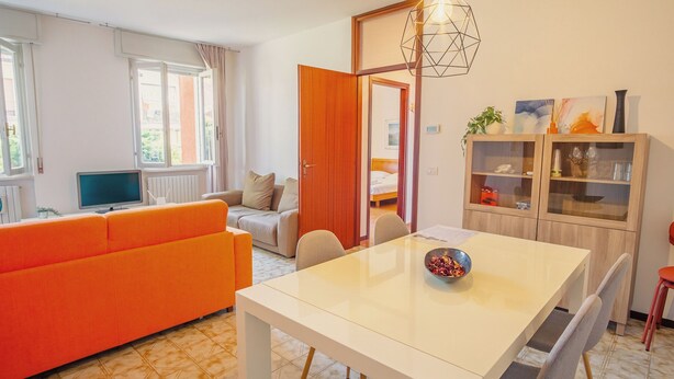 Een moderne woonkamer met een bank, een eettafel, een televisie en een kast.