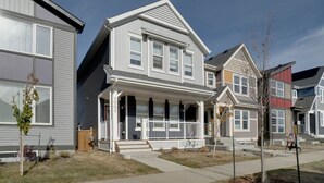 A two-story residential building with a front porch, a garage, and a visible address number. - ModernSuite*NearAirport*2 Queens*ROKU (Edmonton)