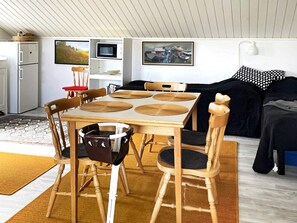 Un espacio habitable compacto con una mesa de comedor, sillas, un sofá y una kitchenette.