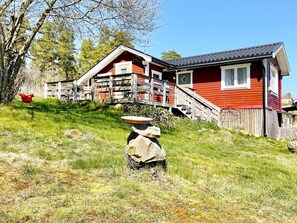 Una casa de madera roja con un balcón y una escultura de piedra al frente.