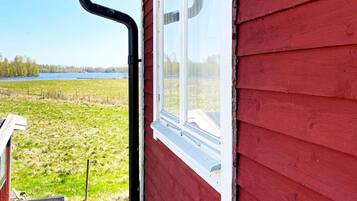 Un edificio rojo con una ventana y vistas a un campo cubierto de hierba y una masa de agua.