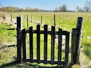 A wooden fence with a gate, surrounded by a grassy field and trees in the background.