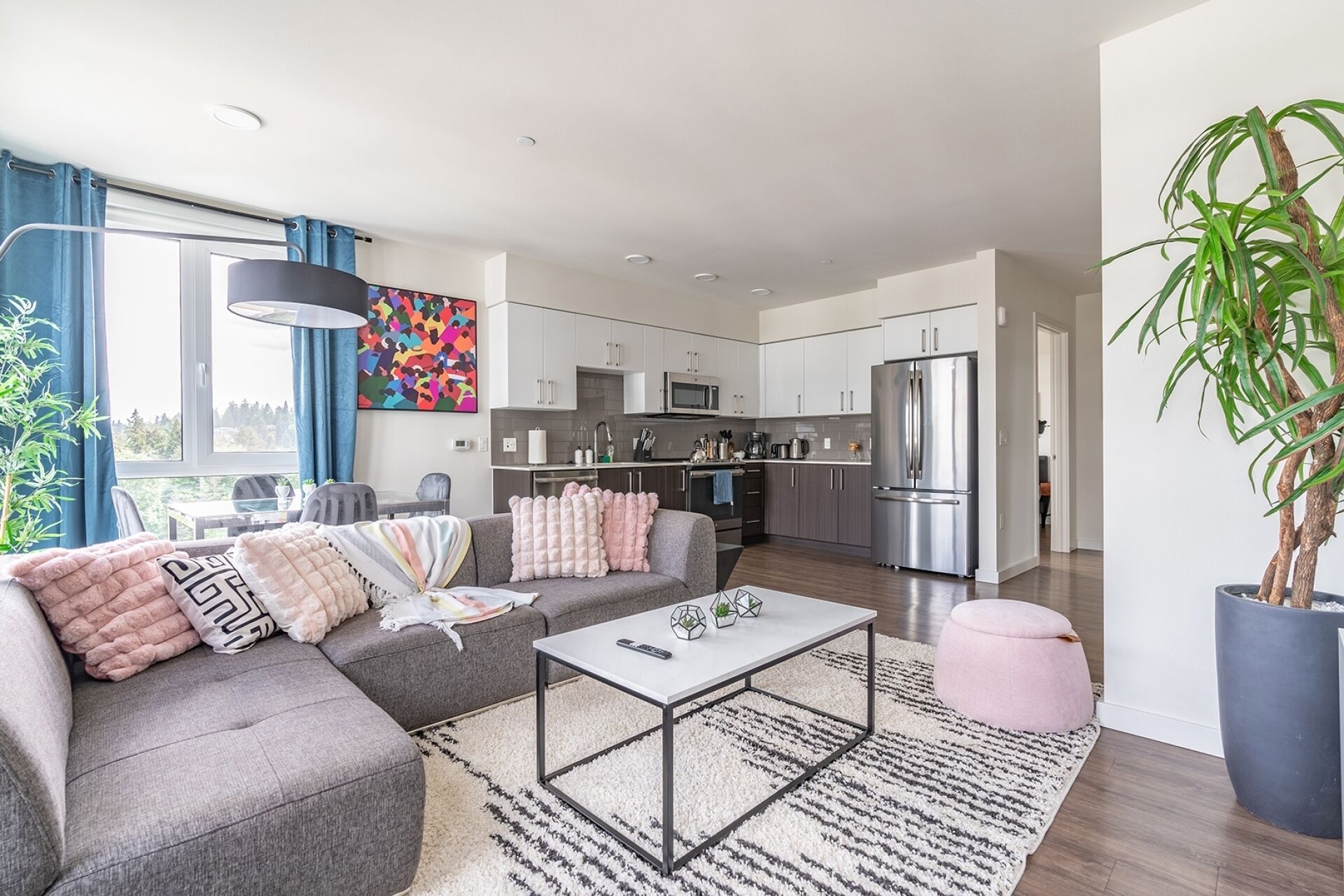 A modern living room with a grey sofa, a coffee table, and a kitchen in the background.