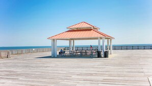 A wooden pier with a gazebo, benches, and a railing.