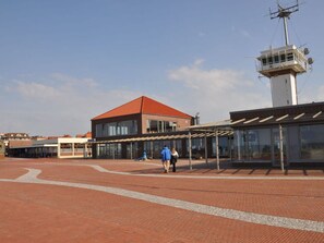 A spacious outdoor area with a covered walkway, a building with a red roof, and a tall structure with antennas. - Strandfleh Modern Retreat (Wangerooge)
