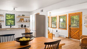 Une cuisine moderne avec des meubles blancs, une table à manger en bois et une grande fenêtre.