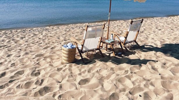 Une plage avec deux chaises longues placées sous un parasol.
