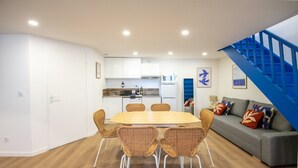 Un espace de vie compact comprenant un coin repas, une kitchenette et un escalier.