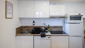Une cuisine moderne avec des armoires blanches, un four à micro-ondes encastré, un lave-vaisselle et un évier.