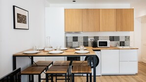 A modern kitchen with wooden cabinets, a microwave, and a dining area with a table and chairs.