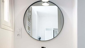 A bathroom with a round mirror, a white sink, and a wooden vanity.