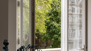 An open door to a balcony with a view of trees and a brick wall. - Balcony South Kensington Luxury 2 bed Apartment (London)