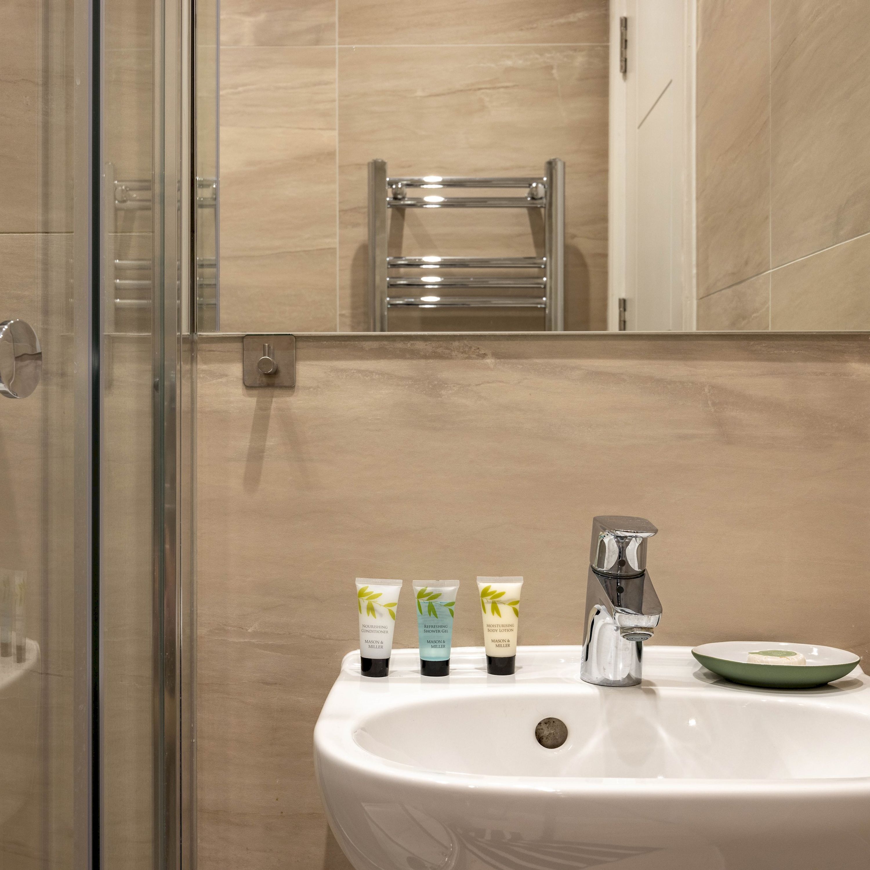 A bathroom with a white sink, three toiletries, a towel rack, and a mirror.