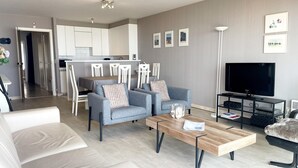 A modern living room with a sofa, armchairs, a coffee table, and a TV. - Apartment in Nieuwpoort by the Beach (Nieuwpoort)