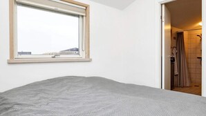Een slaapkamer met een enkel bed, een raam en een deur naar een badkamer.