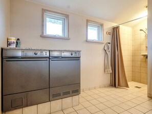 A compact bathroom with two stainless steel appliances, a shower, and a window. - 4 Star Holiday Home in Blokhus (Blokhus)