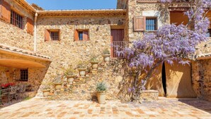 Un edificio de piedra con un patio, una escalera y un árbol de flores moradas.