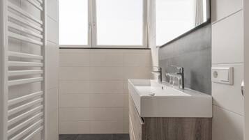 Een moderne badkamer met een wit wastafelmeubel, een spiegel en een raam.