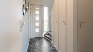 A hallway with a white door, black tiled floor, and a staircase leading to an upper level. - Cozy Holiday Home in Oploo Near Forest (Oploo)