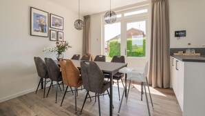 A dining area with a table and chairs, a vase with flowers, and framed pictures on the wall. - Cozy Holiday Home in Oploo Near Forest (Oploo)