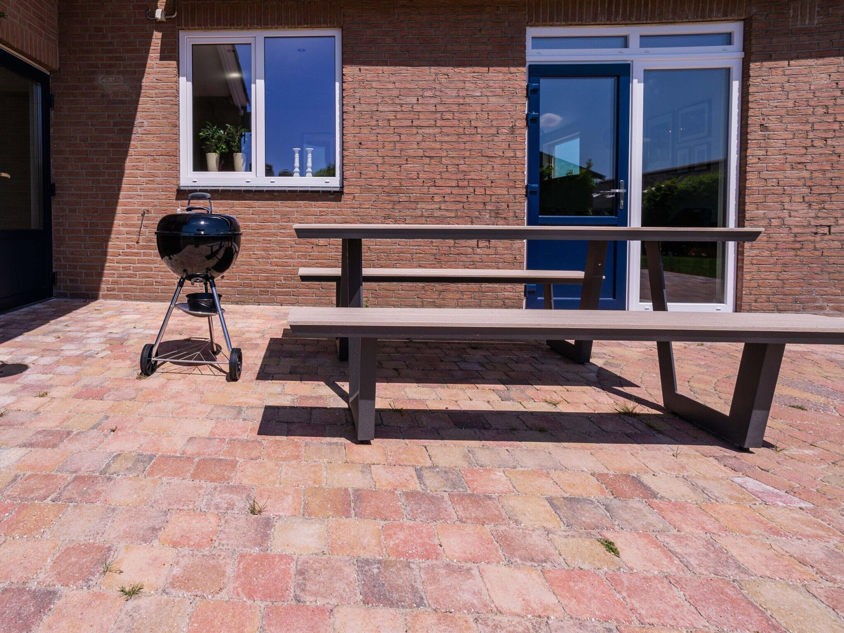 A brick building with a picnic table and a barbecue grill.