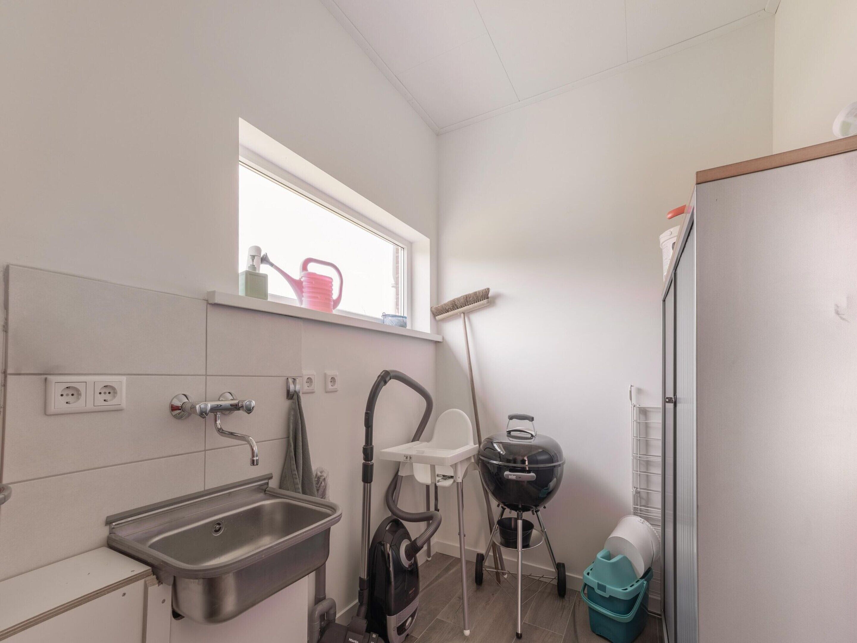 A compact kitchen with a sink, window, and a built-in grill.
