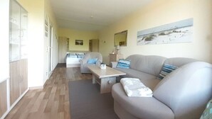 Un salon moderne avec un canapé, une table basse et un lit en arrière-plan.