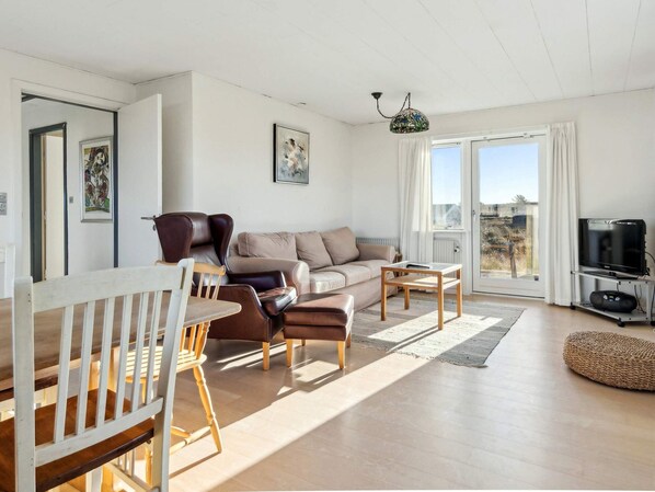A living room with a sofa, chairs, a coffee table, a TV, and a large window.