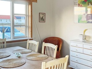 A dining area with a wooden table, four chairs, and a white dresser with drawers.