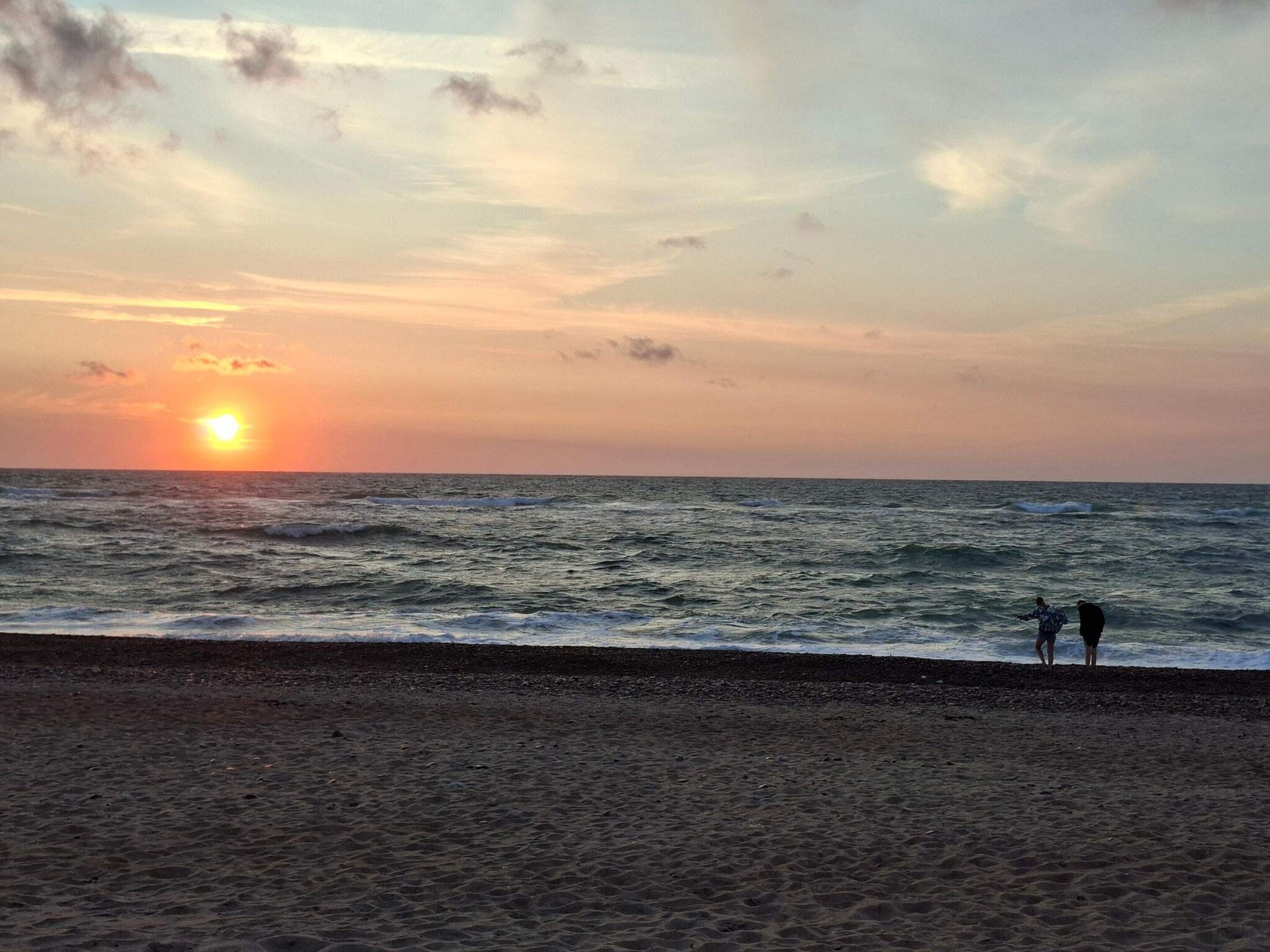 A beach with the ocean and a sunset.