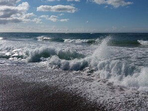 A beach with waves crashing onto the shore under a clear sky.